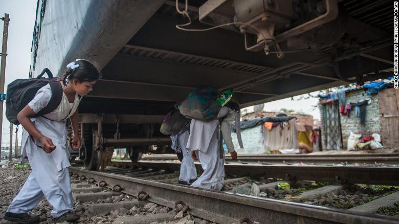 भारत : भारतको नयाँदिल्लीमा स्कुले बालिकाहरु रोकिराखेको रेलमुनीबाट स्कुल जाँदै